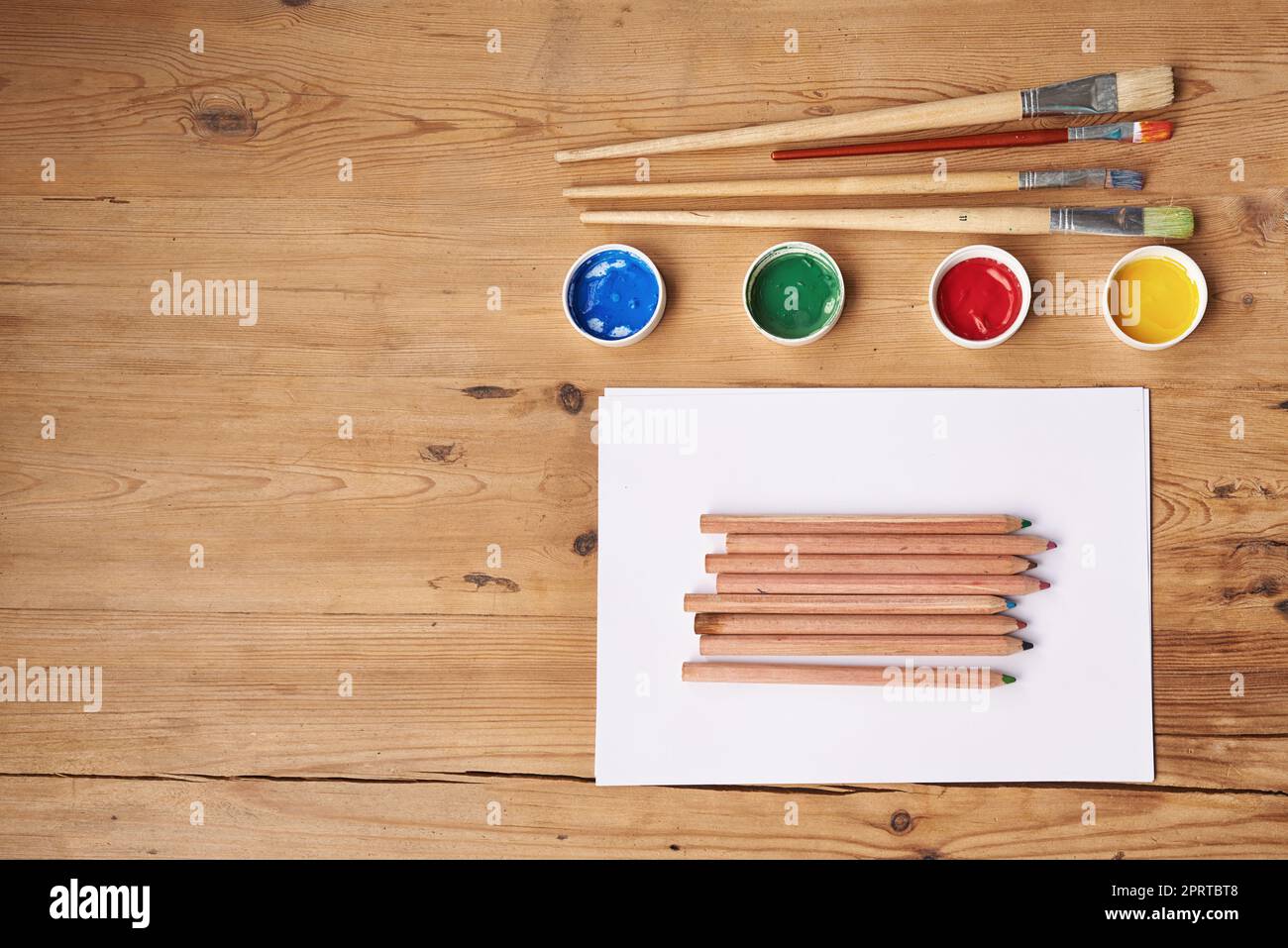 Bereiten Sie sich darauf vor, kreativ zu sein. Leeres Papier mit Malutensilien auf einem Holztisch. Stockfoto