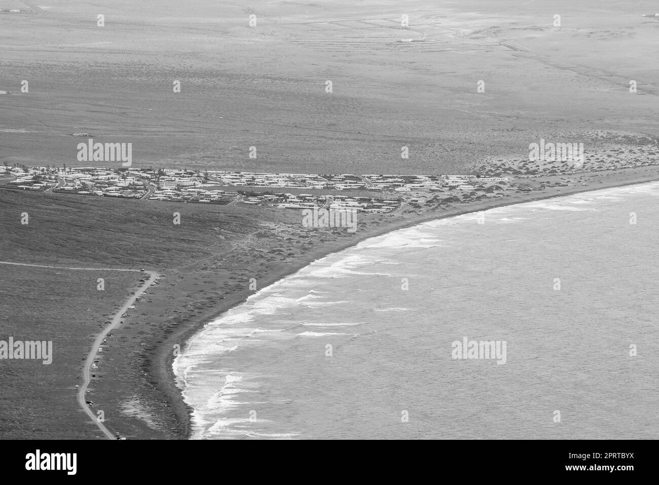 Blick auf Playa de Famara. Blick vom Mirador Rincon de Haria. Super-Zoom-Objektiv. Schwarz und Weiß. Lanzarote. Kanarische Inseln. Spanien. Stockfoto