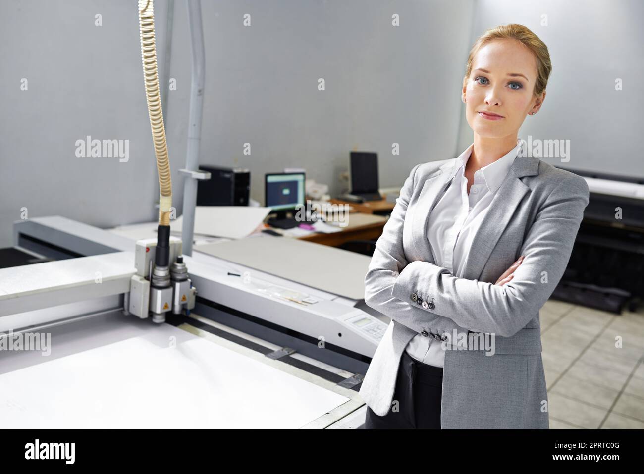 Wenn es druckbar ist, können wir es tun. Ein selbstbewusster junger Verleger, der neben einer Druckmaschine steht. Stockfoto