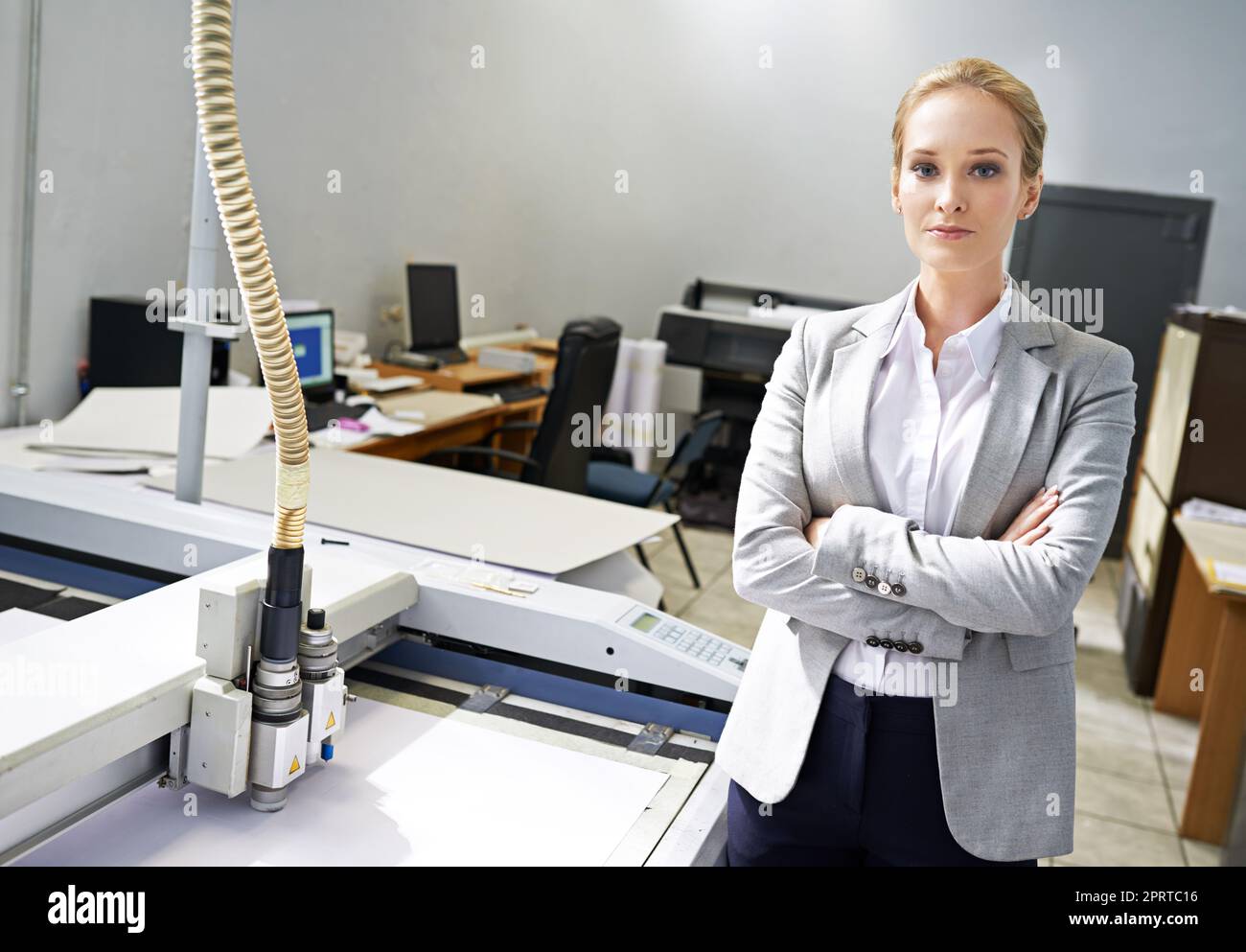 Lassen Sie uns drucken. Porträt eines jungen Vertrauten, der neben einer Druckmaschine steht. Stockfoto