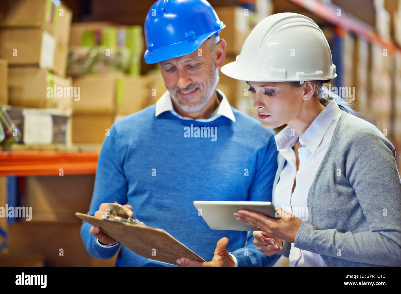 Lassen Sie mich Ihnen zeigen, wie ich diese Zahl erhalten habe. Zwei Personen, die einen Inventarcheck in einem Lager machen. Stockfoto