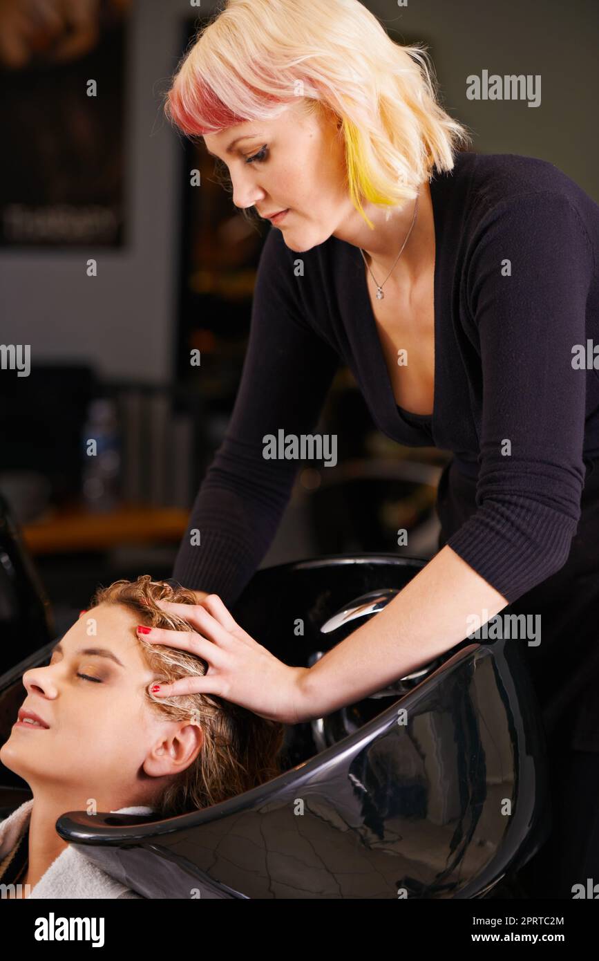 Mein Friseur gibt die besten Kopfmassagen. Eine Frau erhält eine Kopfmassage in einem Friseursalon. Stockfoto