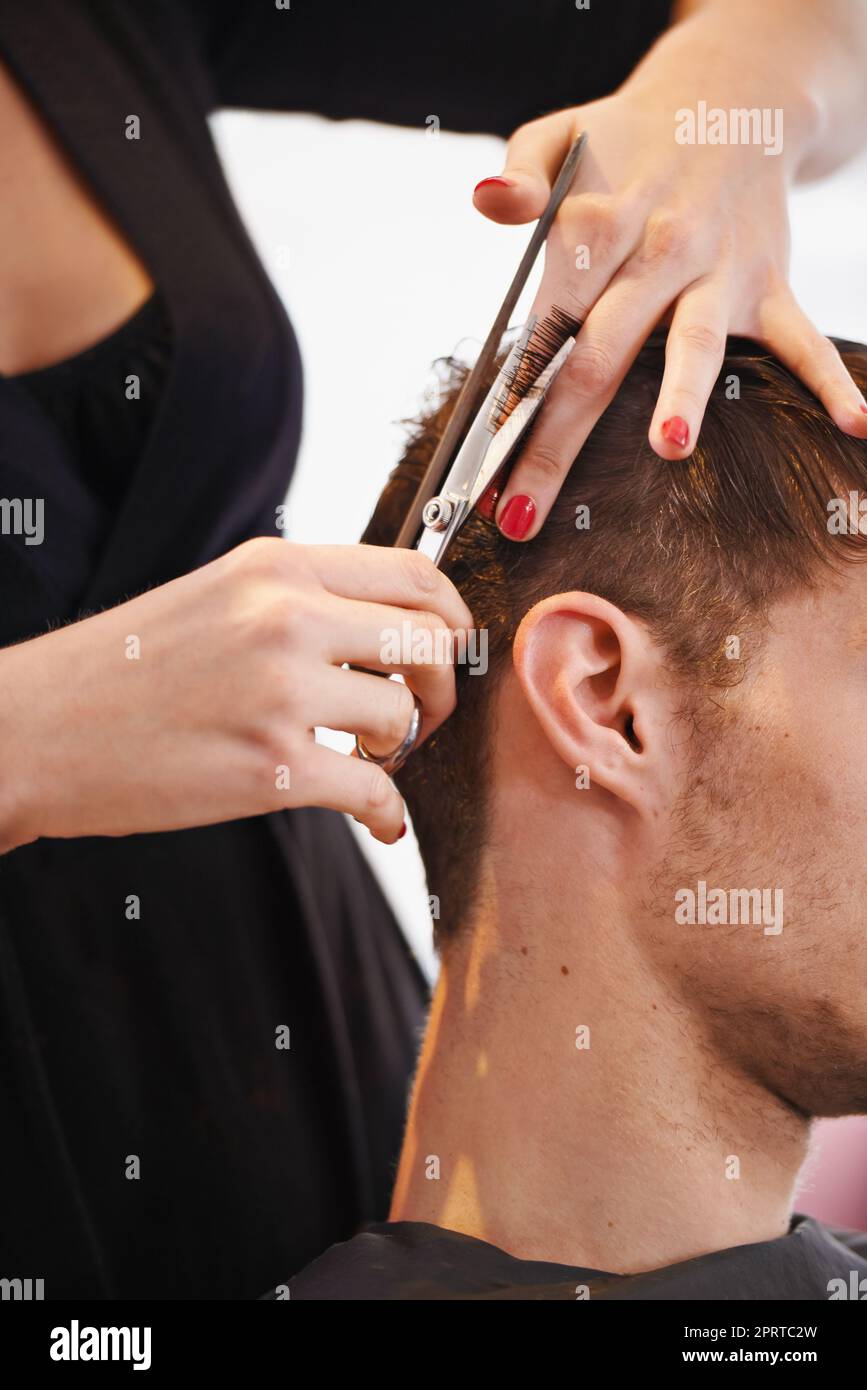 Ein junger Mann, der sich von einem Stylist die Haare schneiden lässt. Stockfoto