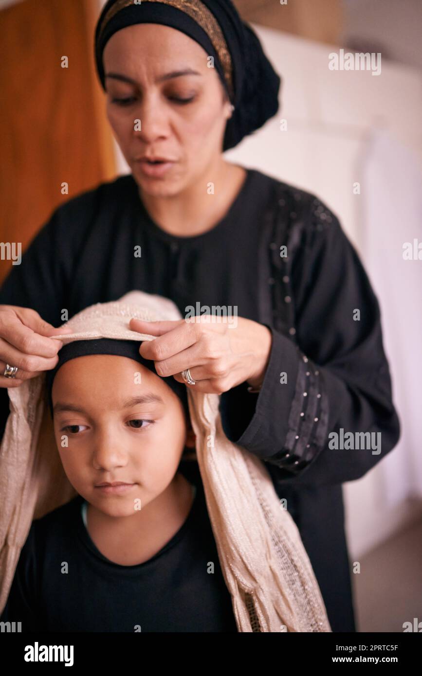 Traditionen sind ein starkes Band. Eine Mutter, die ihrer Tochter hilft, legt ein Kopftuch an. Stockfoto