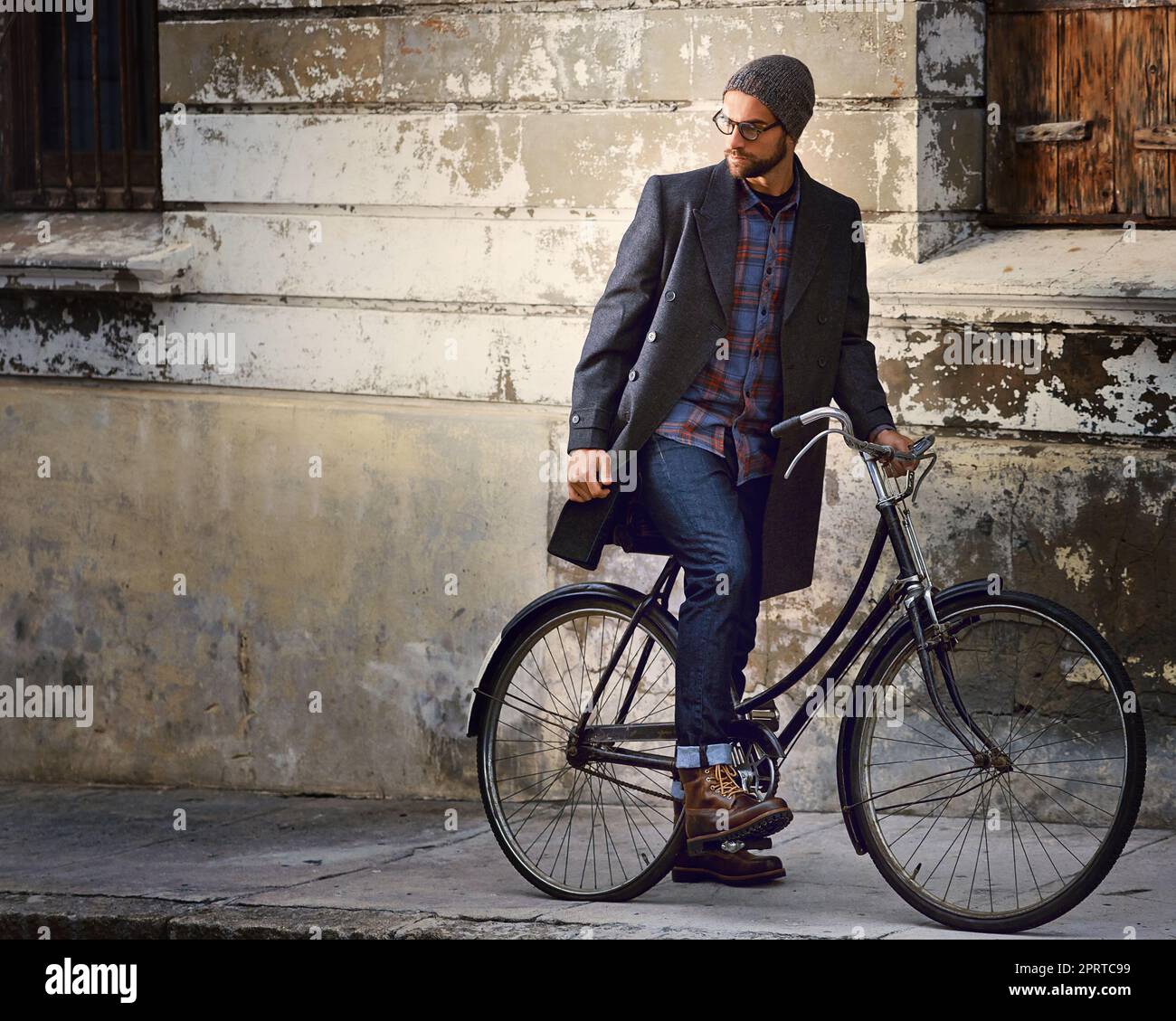 Reisen mit Stil. Ein hübscher junger Mann auf seinem Fahrrad, der sich in der Stadt umherwundert. Stockfoto