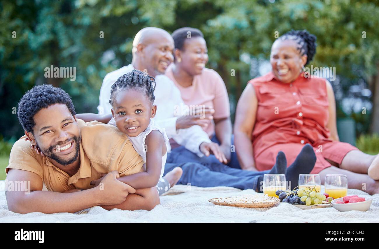 Porträt eines schwarzen Vaters und Kindes bei einem Picknick mit der Familie in einem grünen Garten im Freien im Frühling. Lächeln, glückliche und afrikanische Menschen essen gesunde Früchte bei einer Feier im Freien in einem Park. Stockfoto