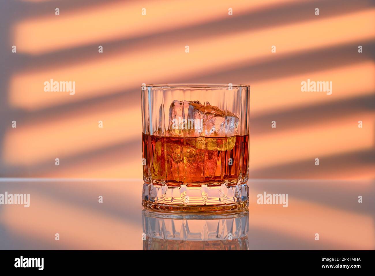 Whiskey mit Eis in Steinglas auf gestreiftem Hintergrund Stockfoto
