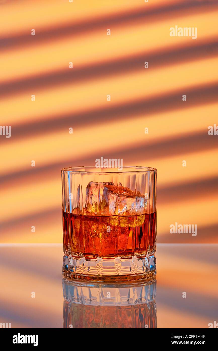 Whiskey mit Eis in Steinglas auf gestreiftem Hintergrund Stockfoto