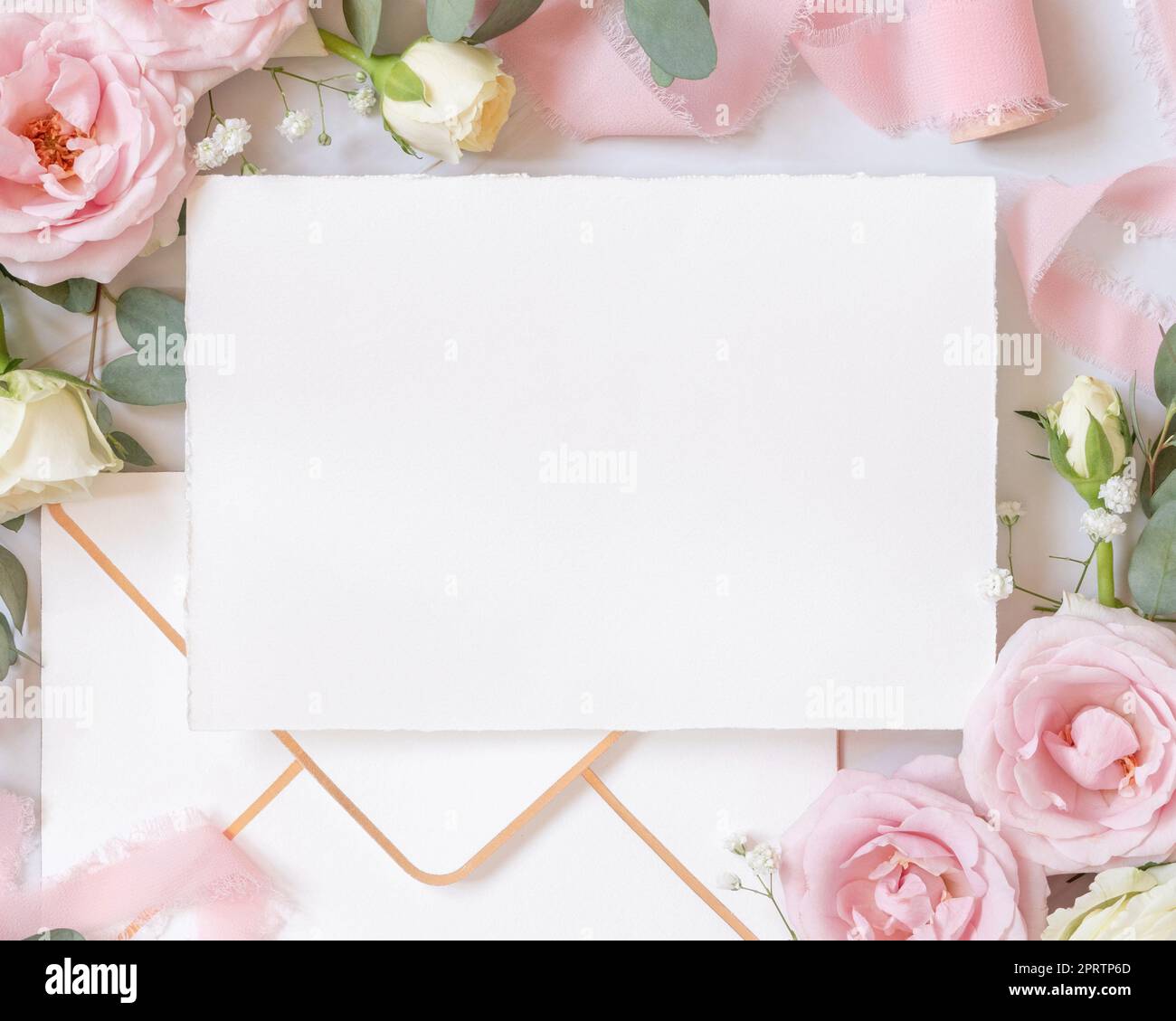 Leere Karte zwischen pinkfarbenen Rosen und pinkfarbenen Seidenbändern, Draufsicht, Hochzeitsmodell Stockfoto