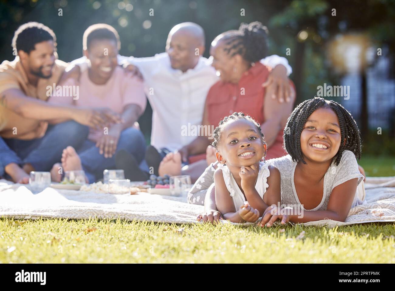 Speisen, Getränke und ein Familienpicknick im Park mit Kindern, Eltern und Großeltern. Männer, Frauen und Kinder entspannen sich in der Natur. Essen, Trinken und Lachen, eine glückliche schwarze Familie draußen mit Mädchen. Stockfoto