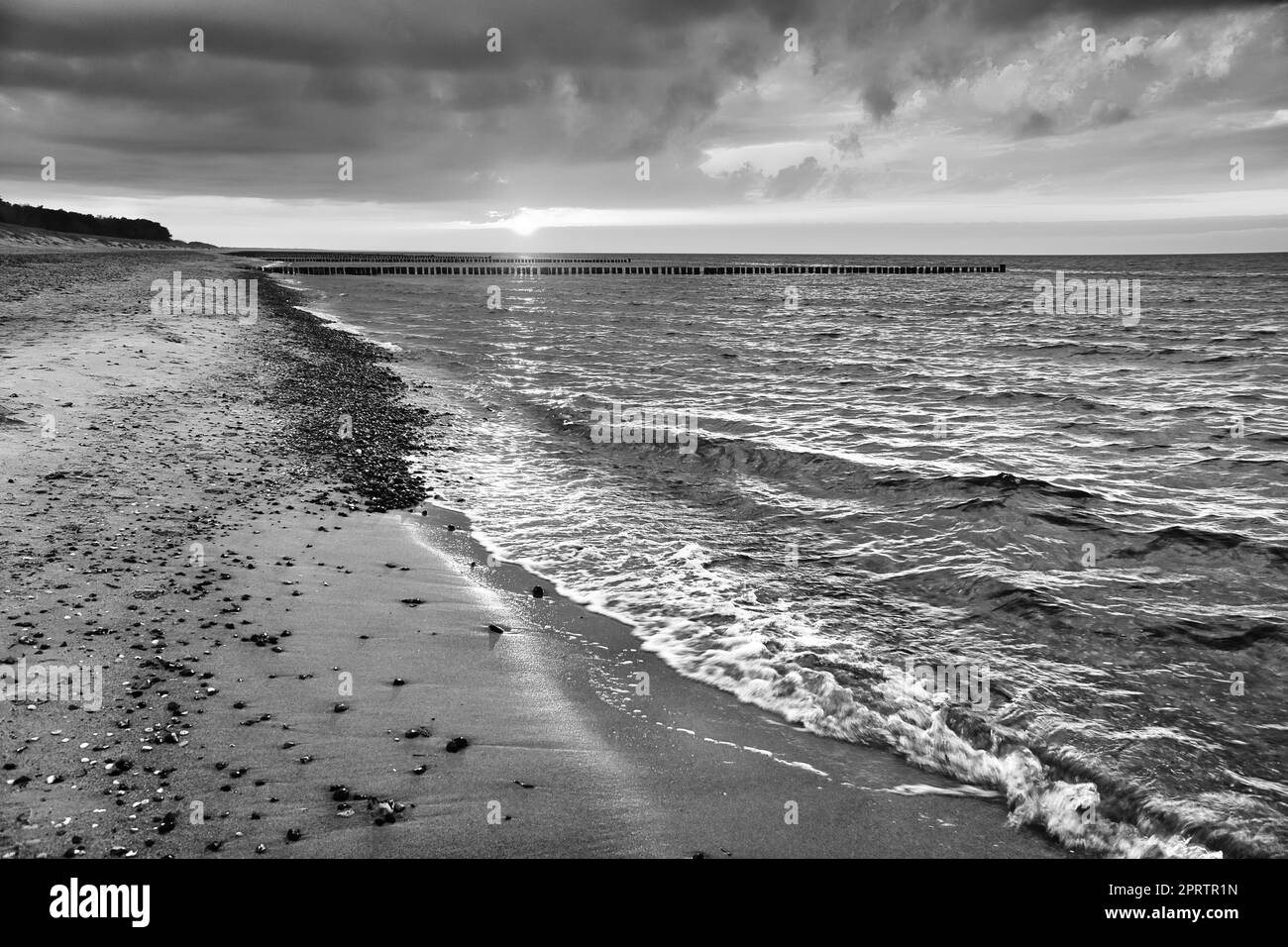 Bei Sonnenuntergang Blick über den Strand in Zingst an der Ostsee. Spazieren Sie in Schwarz-Weiß am Meer entlang. Sich bewegende Wolken am Himmel Stockfoto