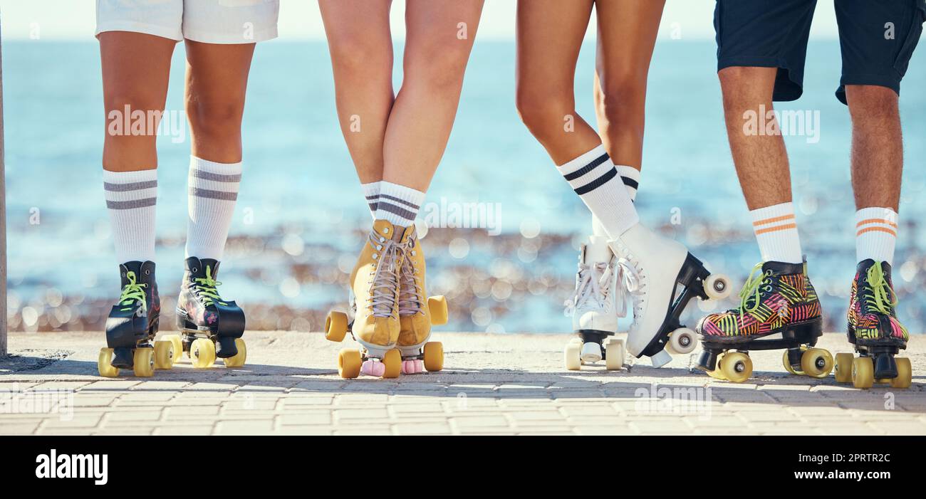 Rollschuhe, Freunde und Strand mit einer Gruppe von Menschen auf der Promenade am Strand mit dem Meer im Hintergrund. Sommer, Spaß und Lifestyle mit Skatern, die an einem sonnigen Tag draußen Schlittschuhlaufen Stockfoto