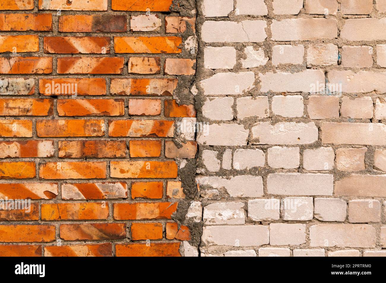 Die Mauer aus roten und weißen Ziegeln ist in zwei Hälften geteilt. Textur, farbiger Hintergrund zur weiteren Verwendung in Grafiken oder Webdesign Stockfoto