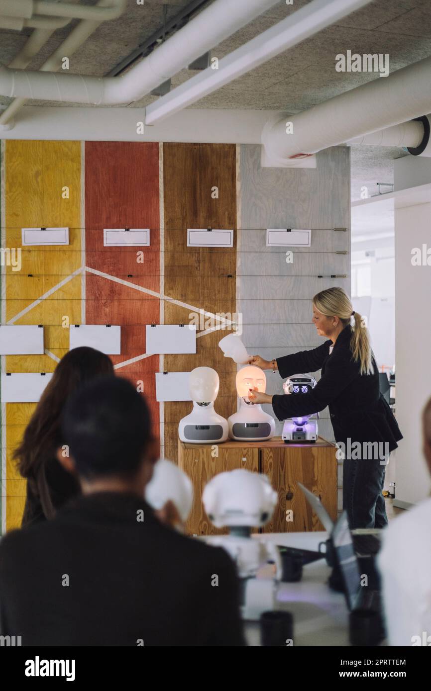 Reife Professorin, die mit Schülern über einen sozialen Roboter im Innovationslabor diskutiert Stockfoto