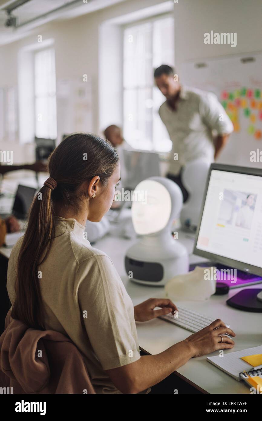 Seitenansicht einer Studentin, die am Schreibtisch sitzt und den Computer benutzt Stockfoto