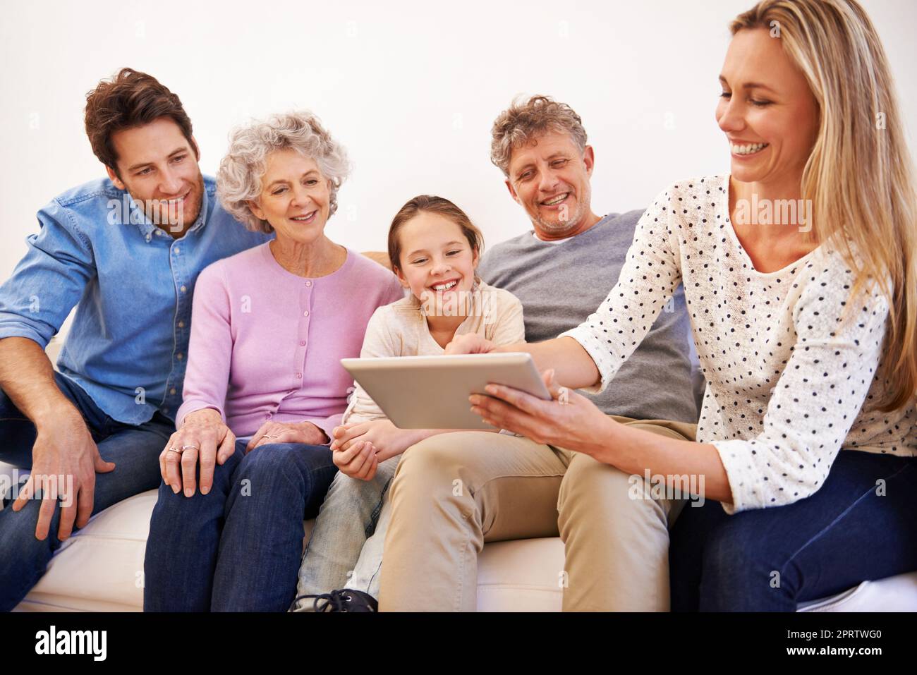 Happy Times Together. Eine glückliche Familie mit mehreren Generationen, die zusammen ein Tablet nutzt. Stockfoto