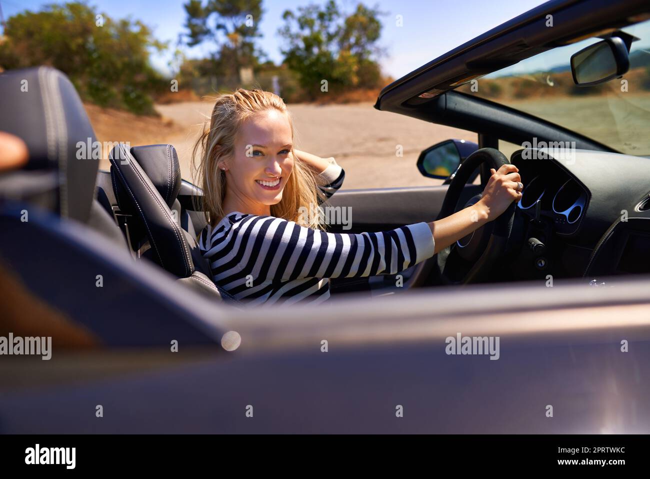 Liebe die offene Straße. Eine junge Frau, die in einem Sportwagen fährt. Stockfoto