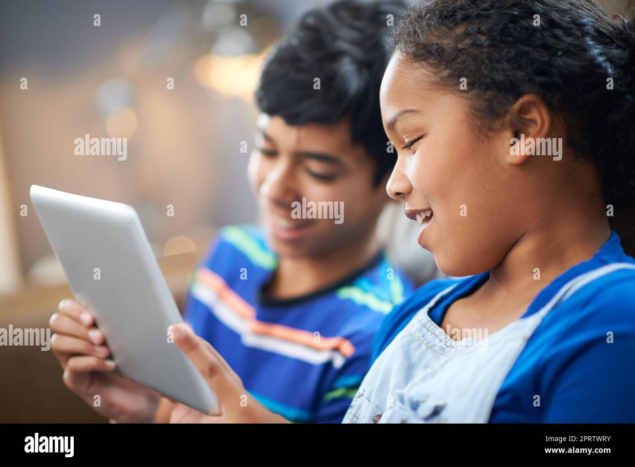 Ein kleiner Bruder und eine Schwester schauen sich etwas auf einem Tablet an. Stockfoto
