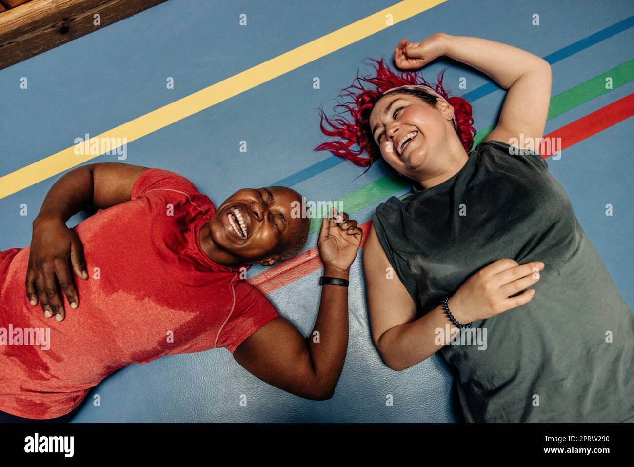 Aus dem Blickwinkel aus dem Blickwinkel heraus lachende Sportlerinnen, die auf einer Sicherheitsmatte auf dem Sportplatz liegen Stockfoto
