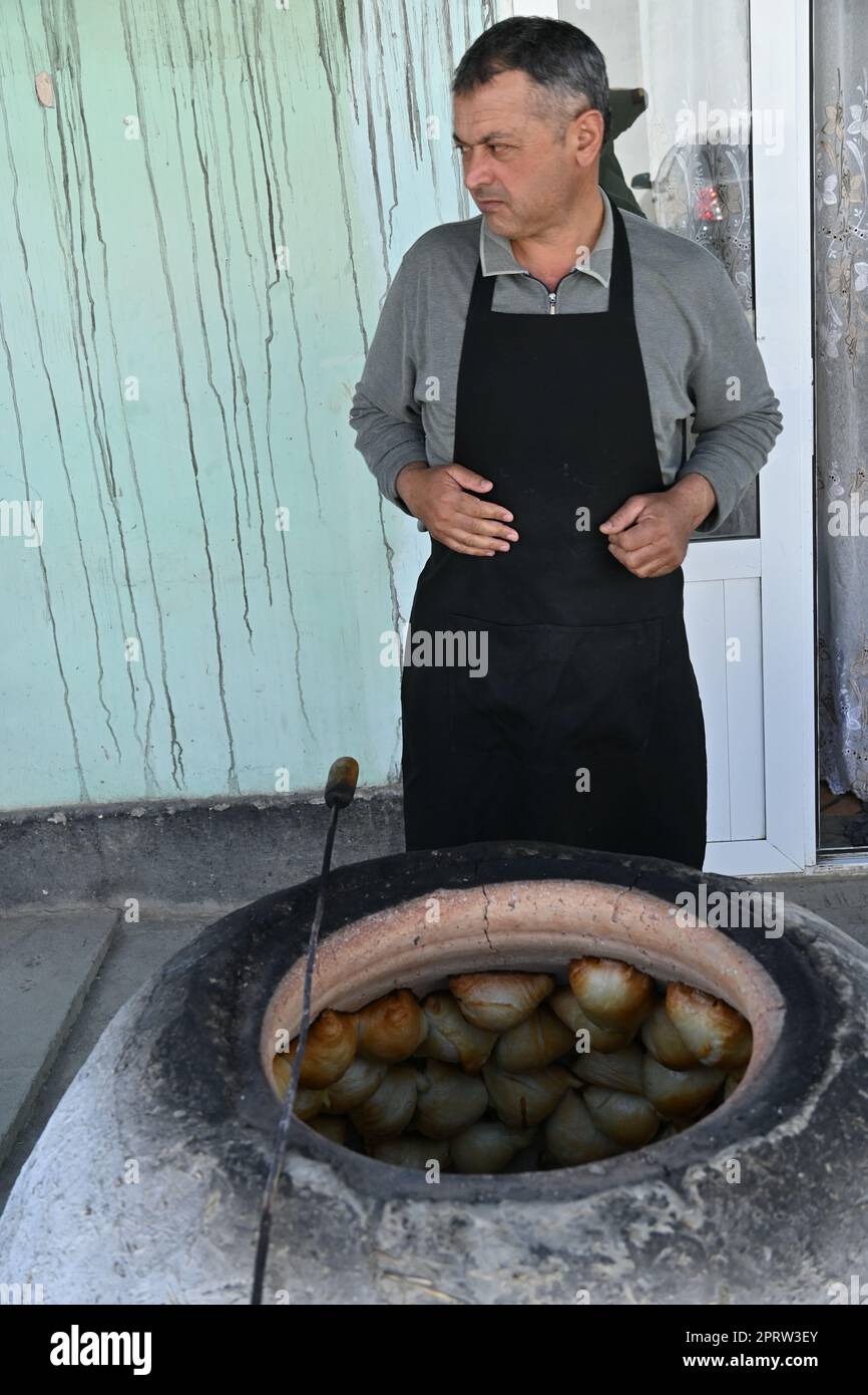 Usbekischer Mann, der in einem Tandir-Ofen in Bukhara, Usbekistan, Somsa, einen traditionellen lokalen Snack, kocht Stockfoto