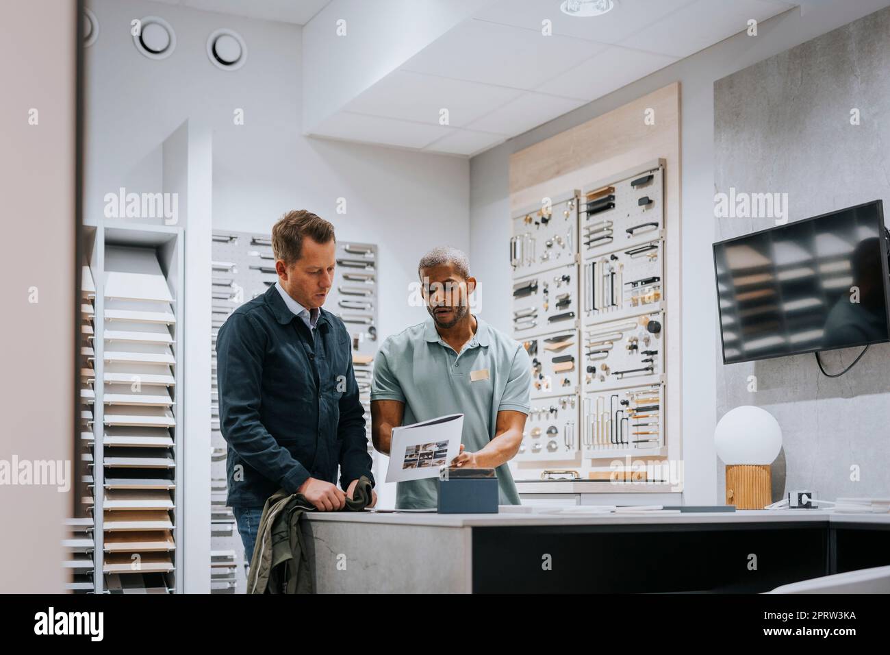 Ein Verkäufer bespricht mit einem erwachsenen Mann über eine Broschüre im Geschäft Stockfoto
