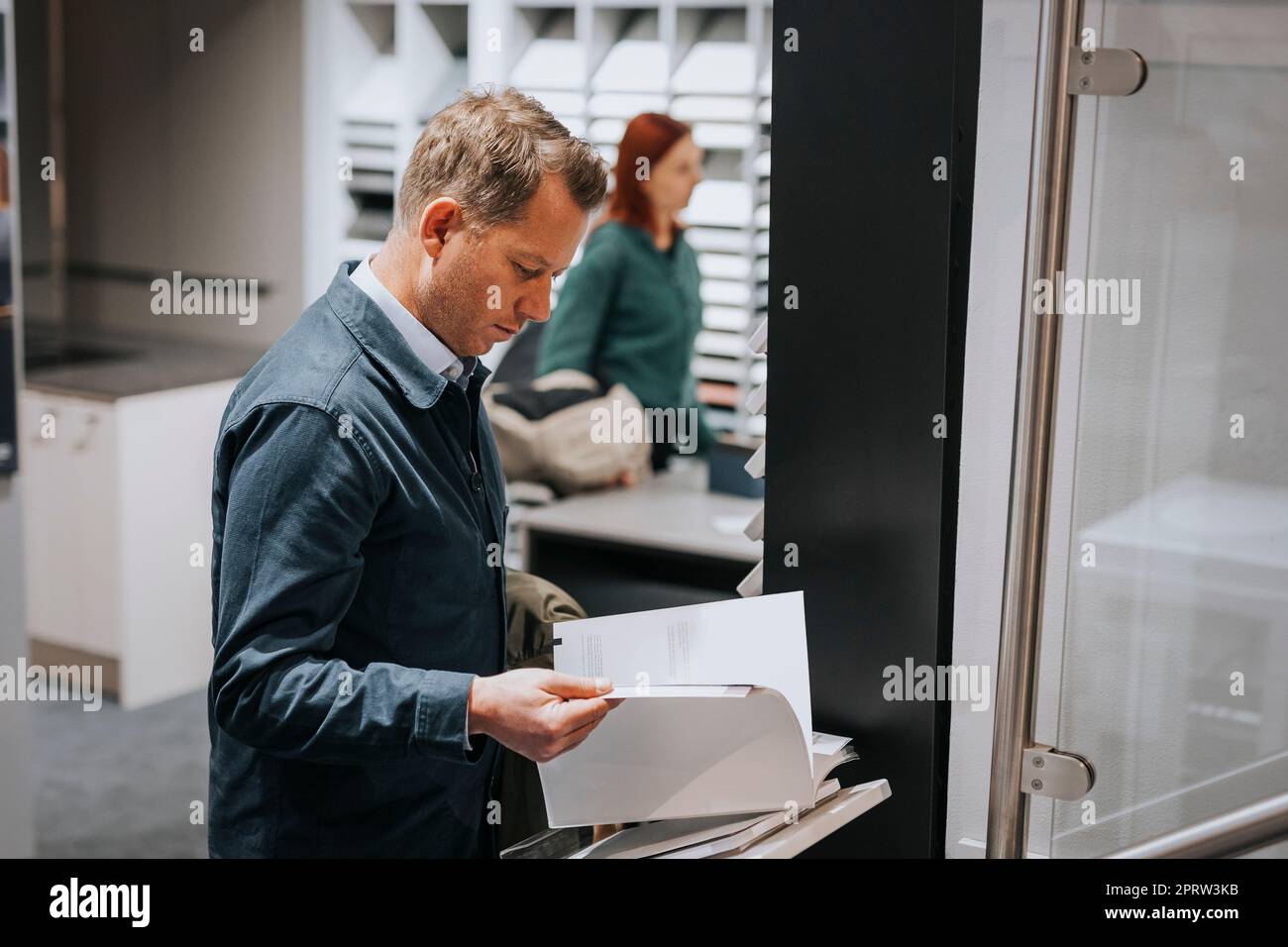 Seitenansicht eines reifen Mannes, der im Elektronikgeschäft Broschüren liest Stockfoto