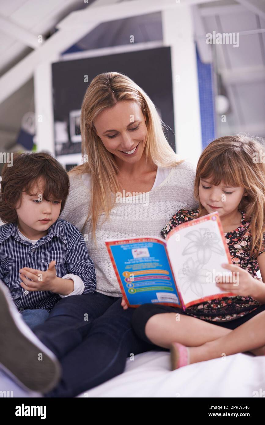 Eine Familie, die zusammen liest... eine Mutter, die mit ihren Kindern zu Hause liest. Stockfoto
