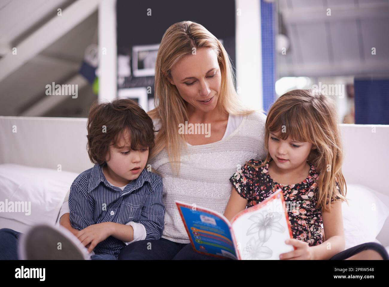 Lesen mit Mama. Eine Mutter liest mit ihren Kindern zu Hause. Stockfoto