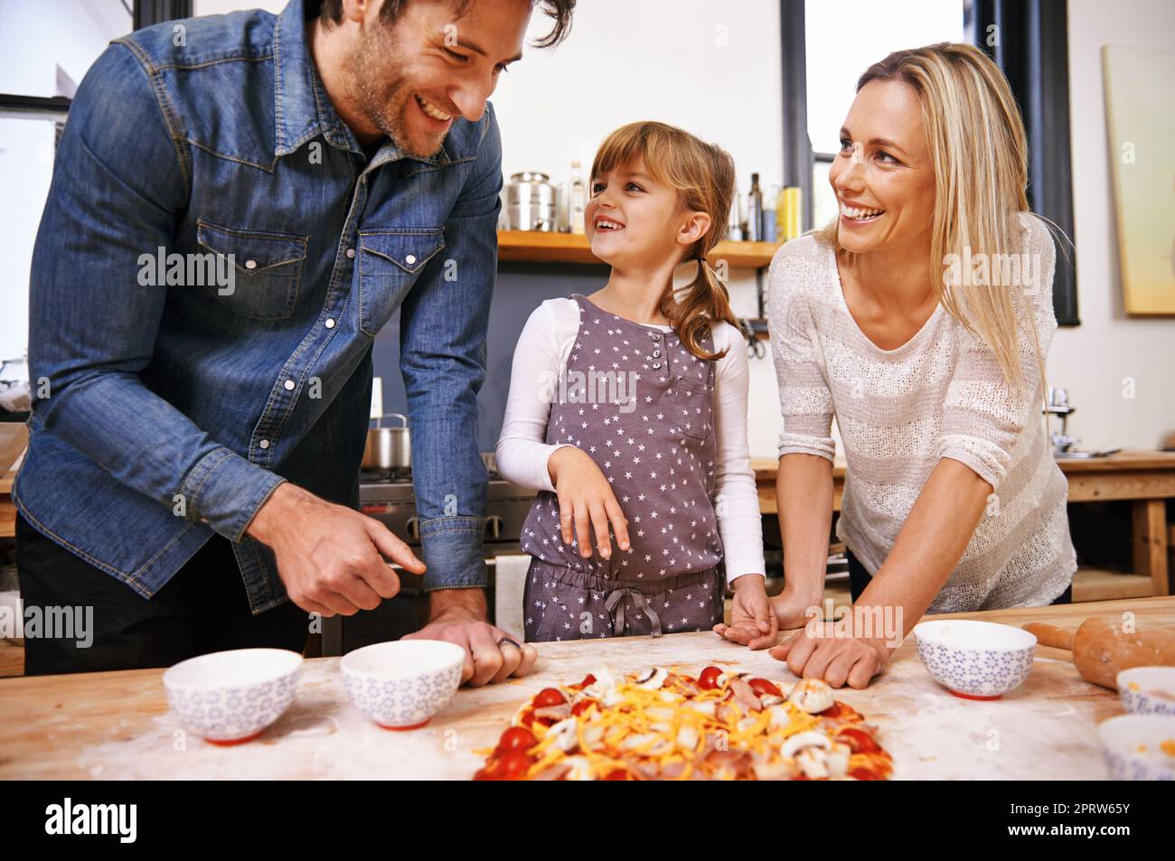 Sieht das okay aus, Papa. Eine Familie, die zu Hause zusammen Pizza macht. Stockfoto