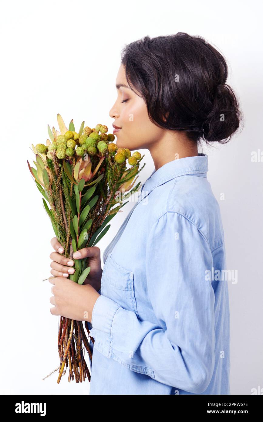 Sich in Naturaroma sonnen. Studioaufnahme einer attraktiven jungen ethnischen Frau mit einem Blumenstrauß. Stockfoto