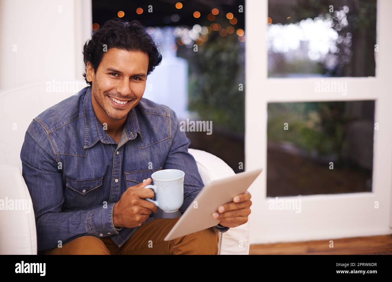 Komfort nach der Arbeit. Porträt eines gutaussehenden Mannes, der sein Tablet benutzt, während er sich zu Hause entspannt. Stockfoto