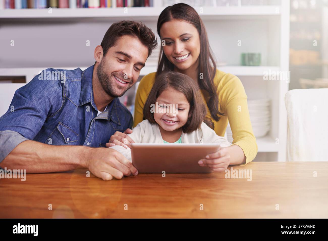 Es ist ein wunderbares Lehrmittel. Junge Eltern zeigen ihrer kleinen Tochter, wie man eine Tablette verwendet. Stockfoto