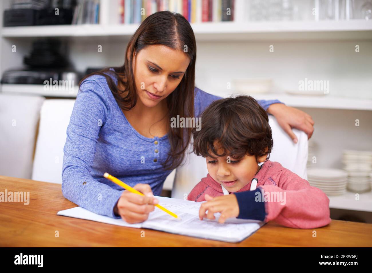 Hausaufgaben machen mir mehr Spaß, wenn Mama mir dabei hilft. Eine Mutter hilft ihrem Sohn bei seinen Hausaufgaben. Stockfoto