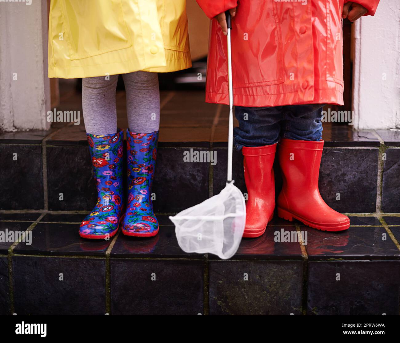 Bereit für den Regen. Zwei Kinder in Regenmänteln und Galoschen gekleidet. Stockfoto