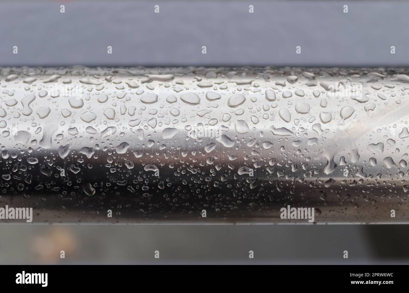 Regentropfen auf einer schwarzen metallischen Oberfläche in der Nahaufnahme. Stockfoto