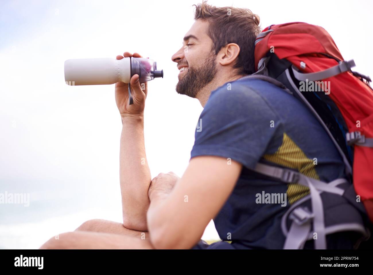 Zeit zum Auftanken. Ein gutaussehender Mann, der an einem sonnigen Tag eine Pause von seiner Wanderung einlegte. Stockfoto