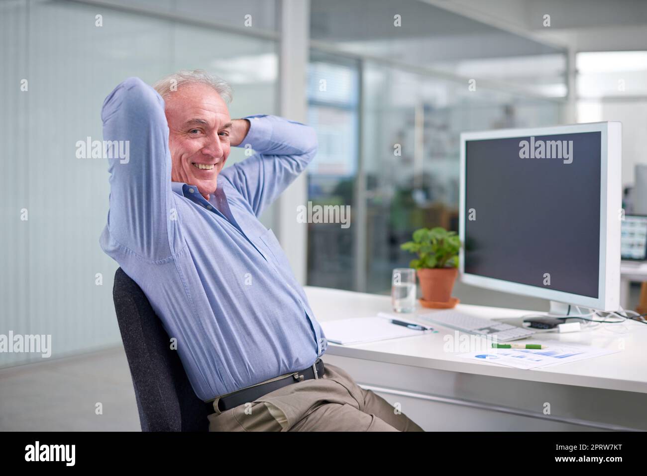 Er genießt seinen Job viel zu sehr, um in den Ruhestand zu gehen. Porträt eines entspannten, reifen Geschäftsmannes, der an seinem Schreibtisch sitzt. Stockfoto