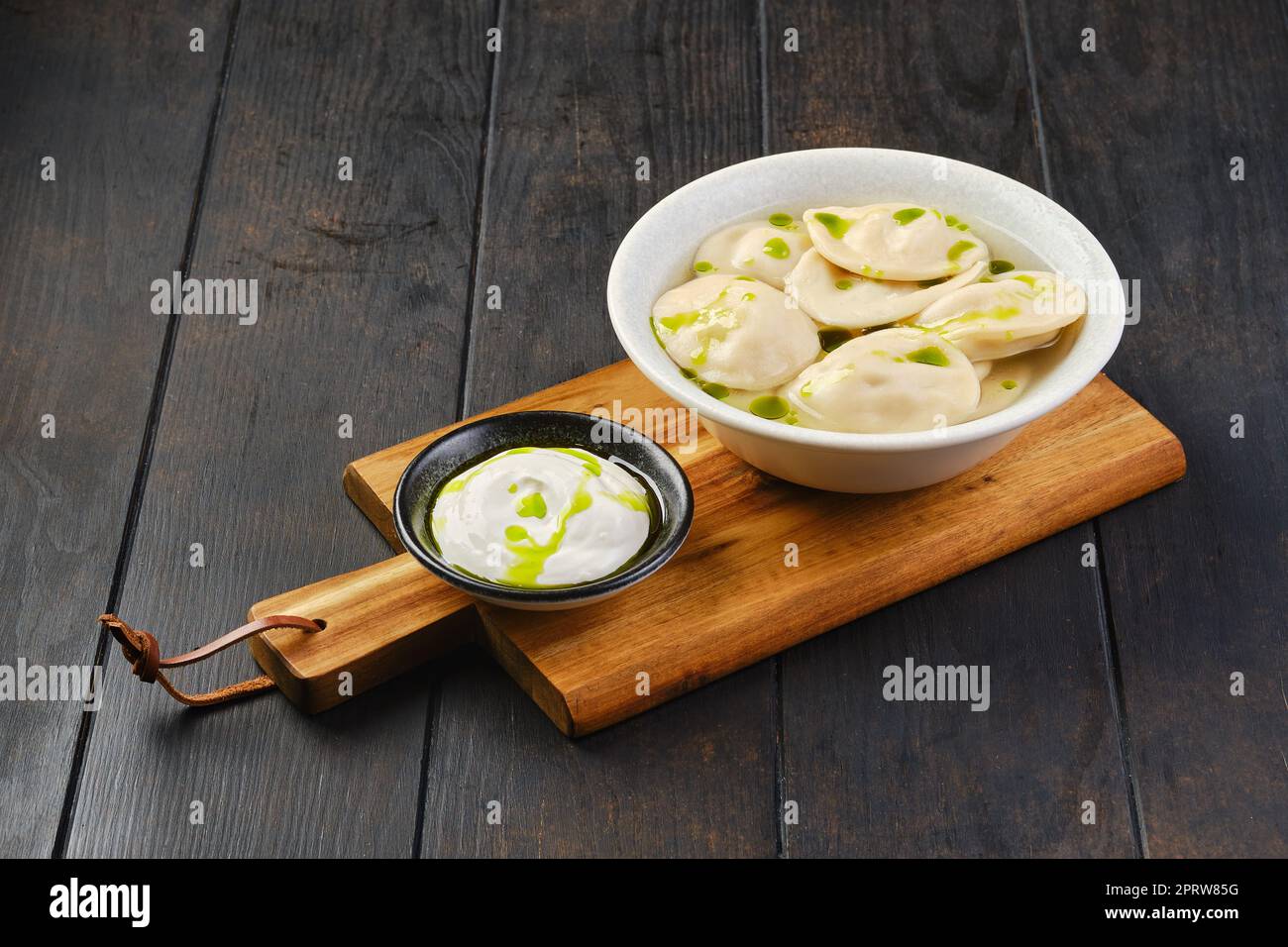 Schüssel mit Rinderknödeln mit Sauerrahm auf einem hölzernen Servierbrett Stockfoto