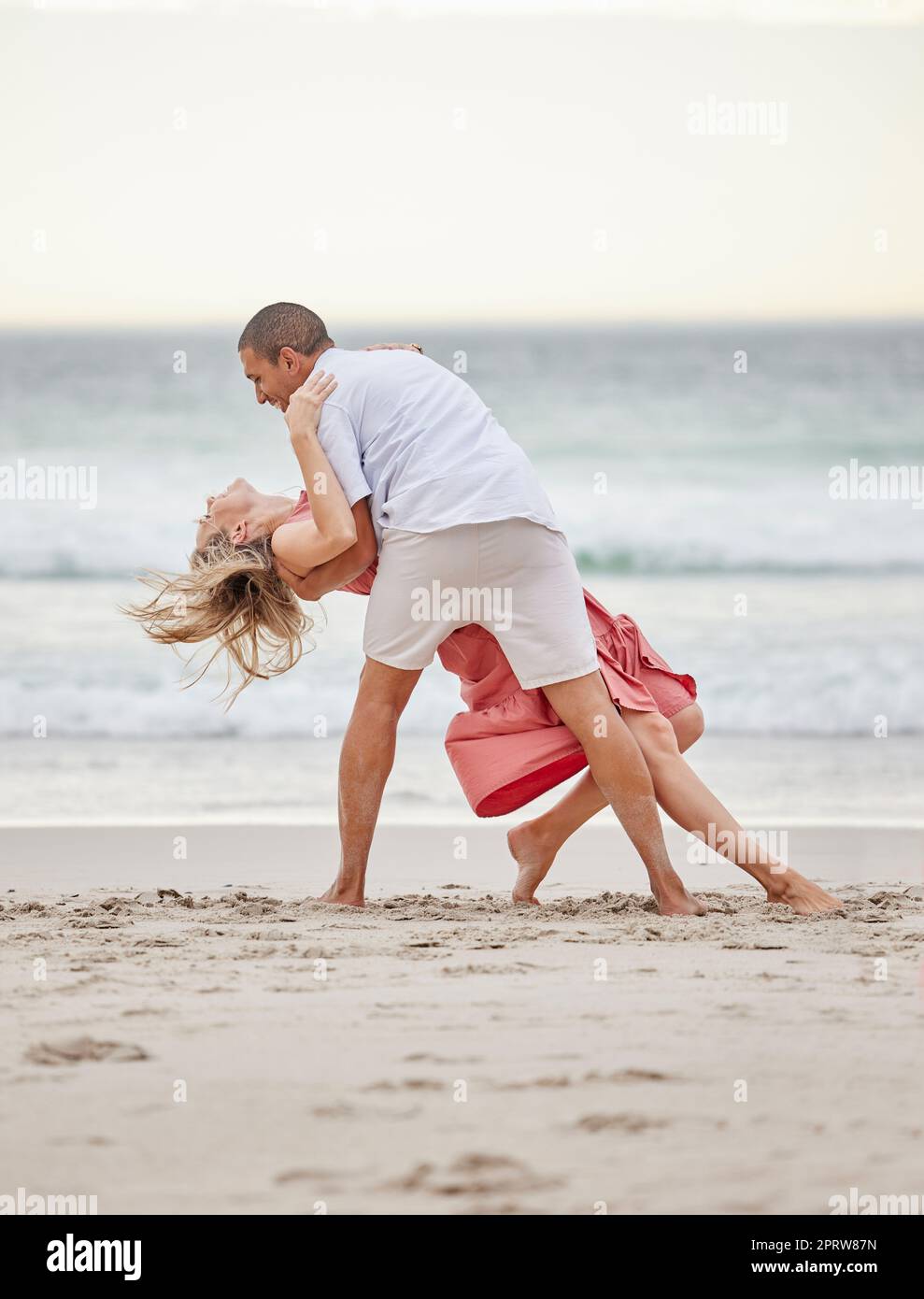 Tanzen, glückliches Paar und Strand feiern Liebe, Vertrauen und Engagement auf romantischen Luxusurlaub Bali Urlaub. Mann und Frau oder Tänzerpaarfeier auf Meerwasser, Sand und Sonnenuntergang Ozean Stockfoto