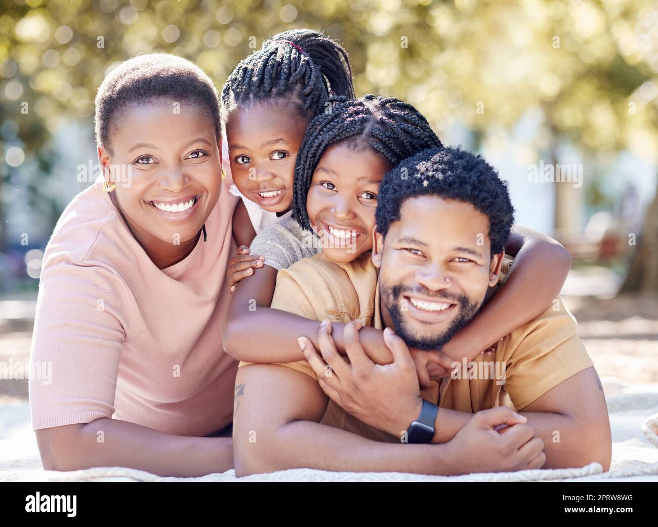 Die afrikanische Familie lächelt im Park, hat Spaß in der Sommersonne und genießt die Natur im Urlaub. Schwarzer afrikanischer Mann, lächelnde Frau und Kinder. Kinder umarmen Dad, um sich mit Eltern im Garten zu verbinden Stockfoto