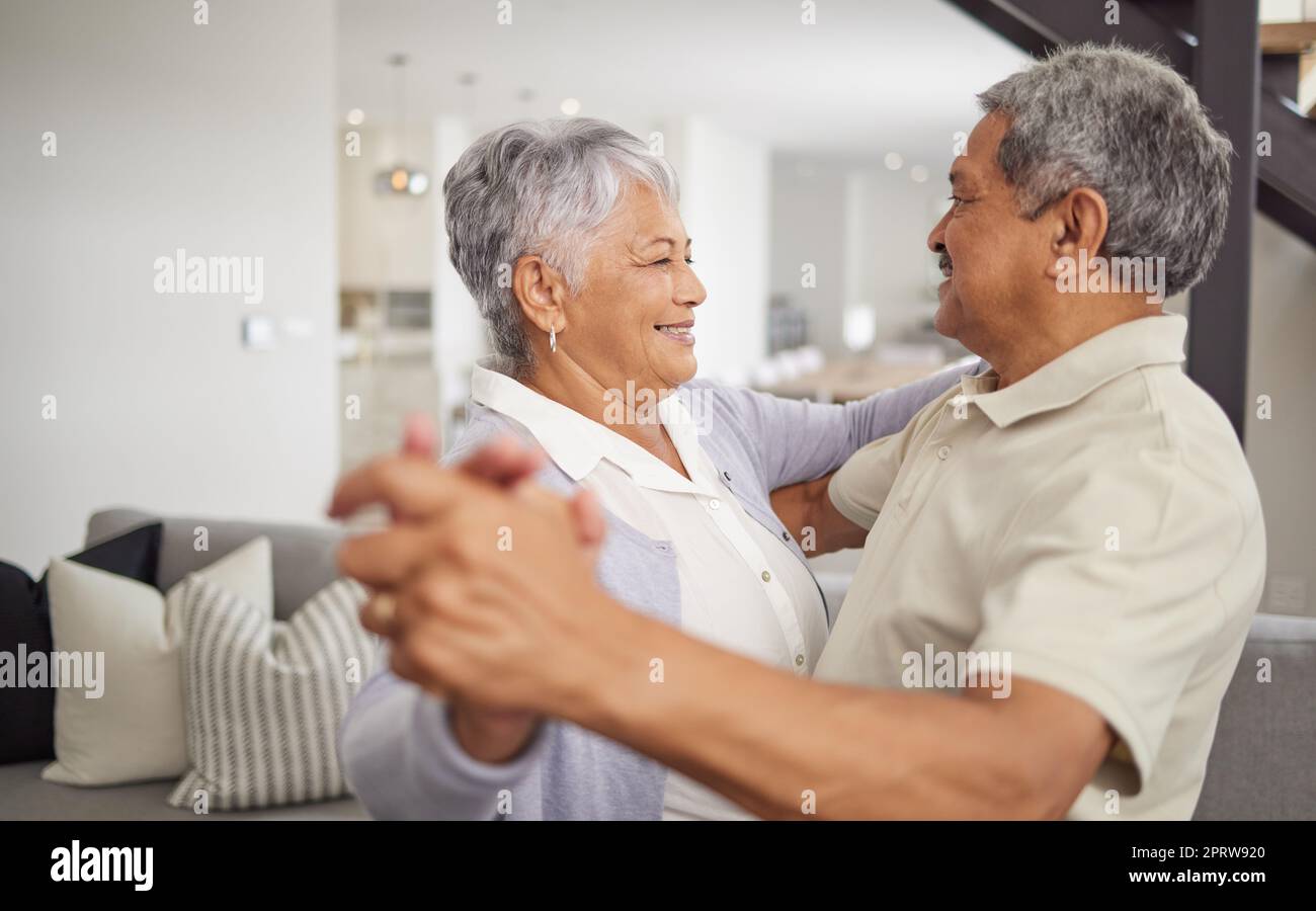 Liebe, Tanz und Glück mit einem Seniorenpaar, das verspielt und romantisch ist, während es sein Jubiläum oder den Ruhestand zu Hause feiert. Glücklicher Mann und glückliche Frau, die sich in einer gesunden Beziehung verbinden Stockfoto