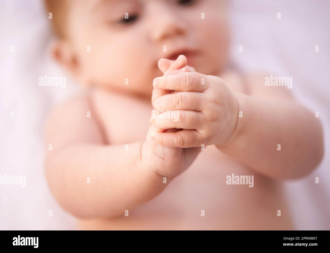 Findet ihre Finger. Eine kurze Aufnahme eines entzückenden Mädchens, das auf einer Decke liegt. Stockfoto