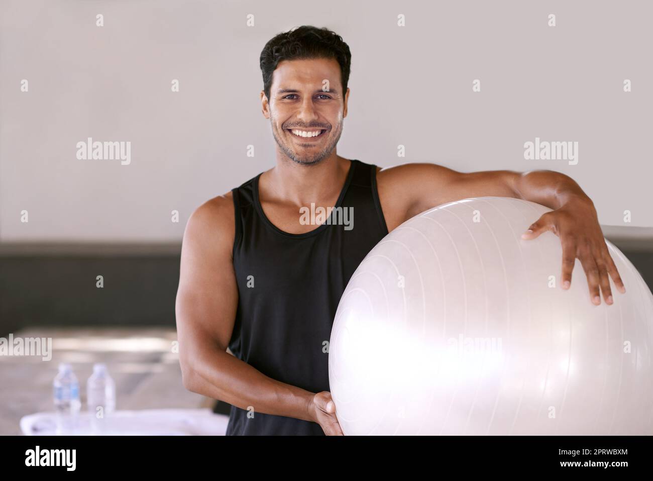 Zeit für ein Workout. Porträt eines hübschen Mannes, der mit einem Übungsball steht. Stockfoto