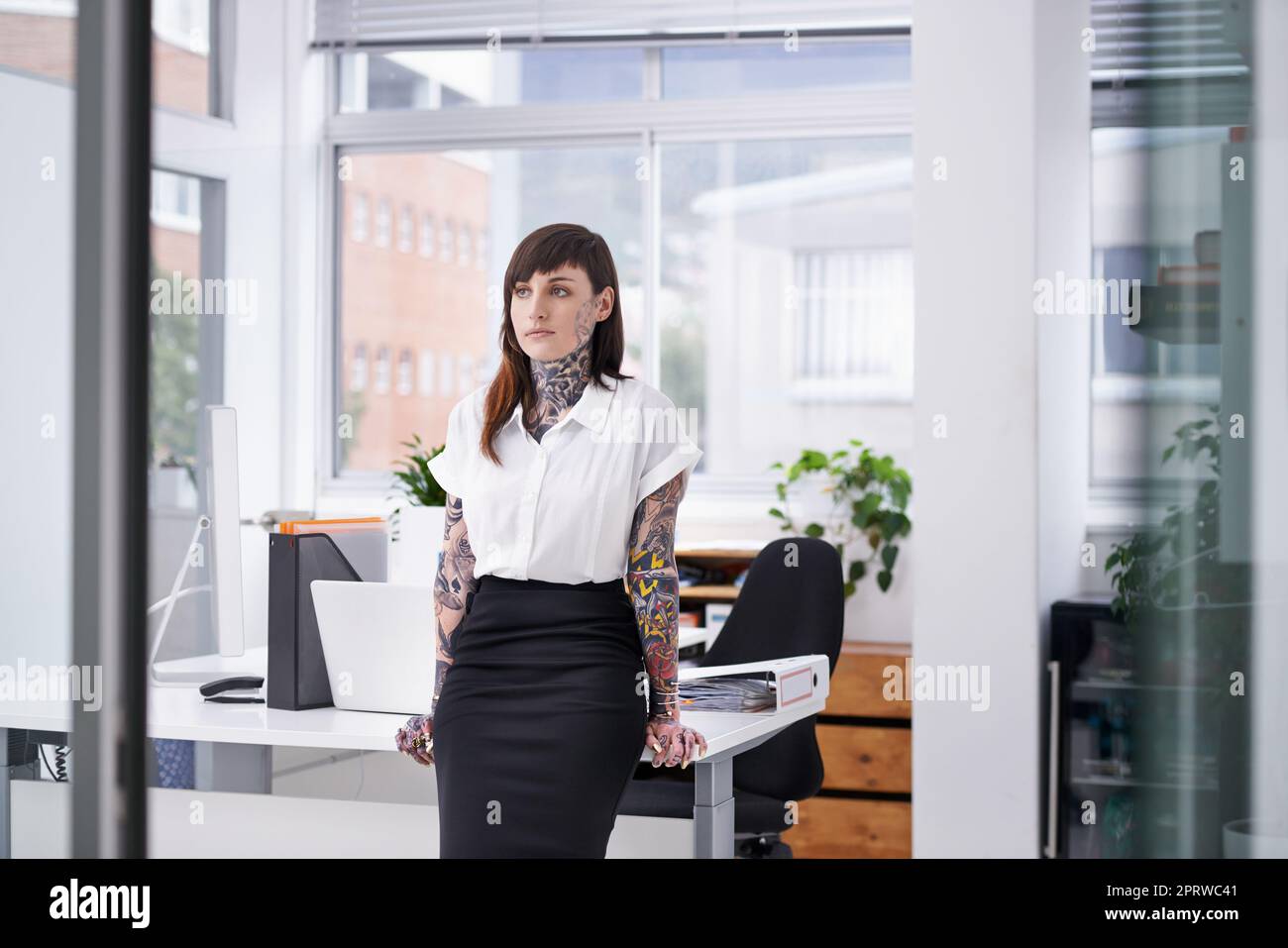 Shes bereit, die Unternehmensszene zu rocken. Eine mit Tätowierungen bedeckte junge Geschäftsfrau in ihrem Büro. Stockfoto