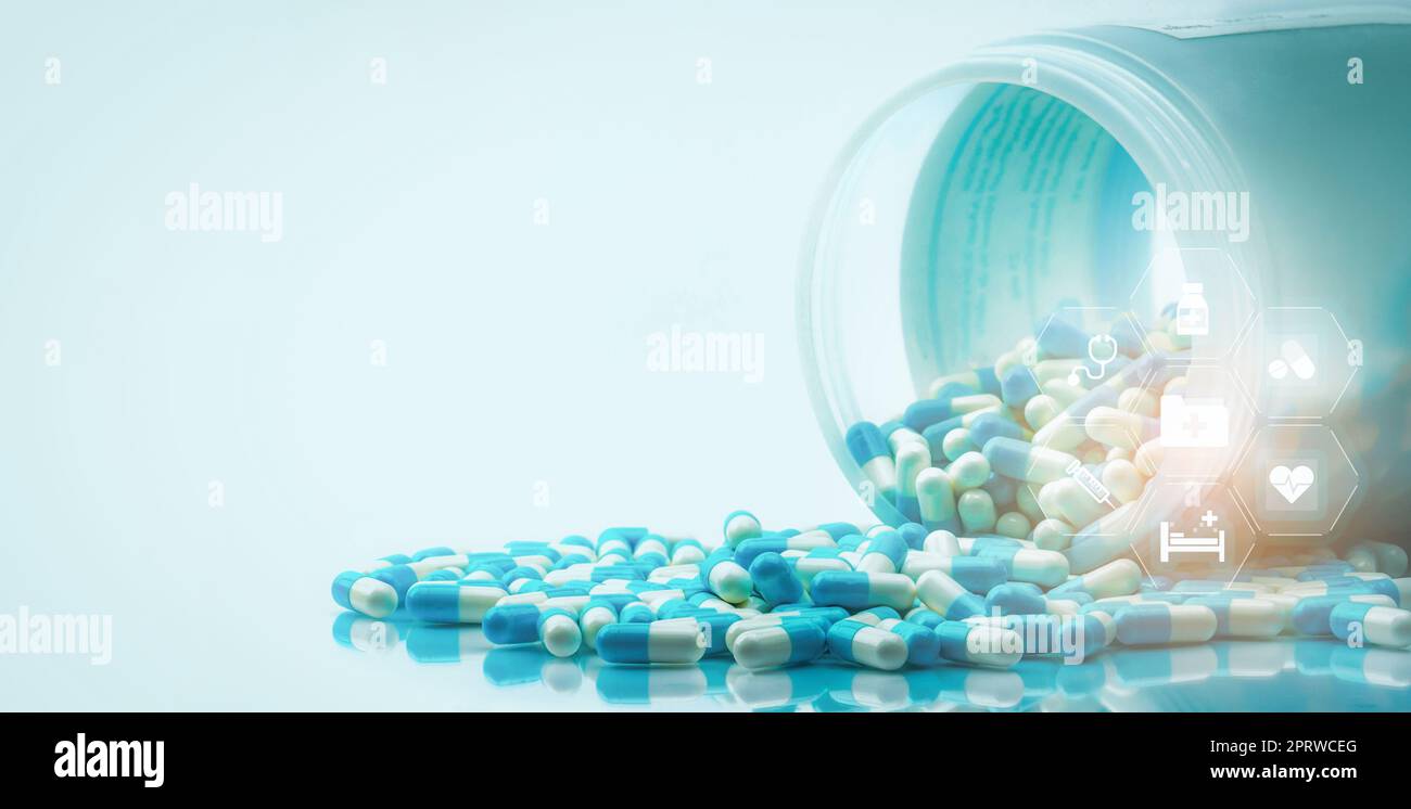 Blaue und weiße Kapseln Pillen verschüttet aus weißer Plastikflasche mit medizinischem und Healthcare Symbol. Medizin- und Gesundheitskonzept. Krankenhausbetreuung und Krankenkassendienst. Krankenhaushaushalt. Stockfoto