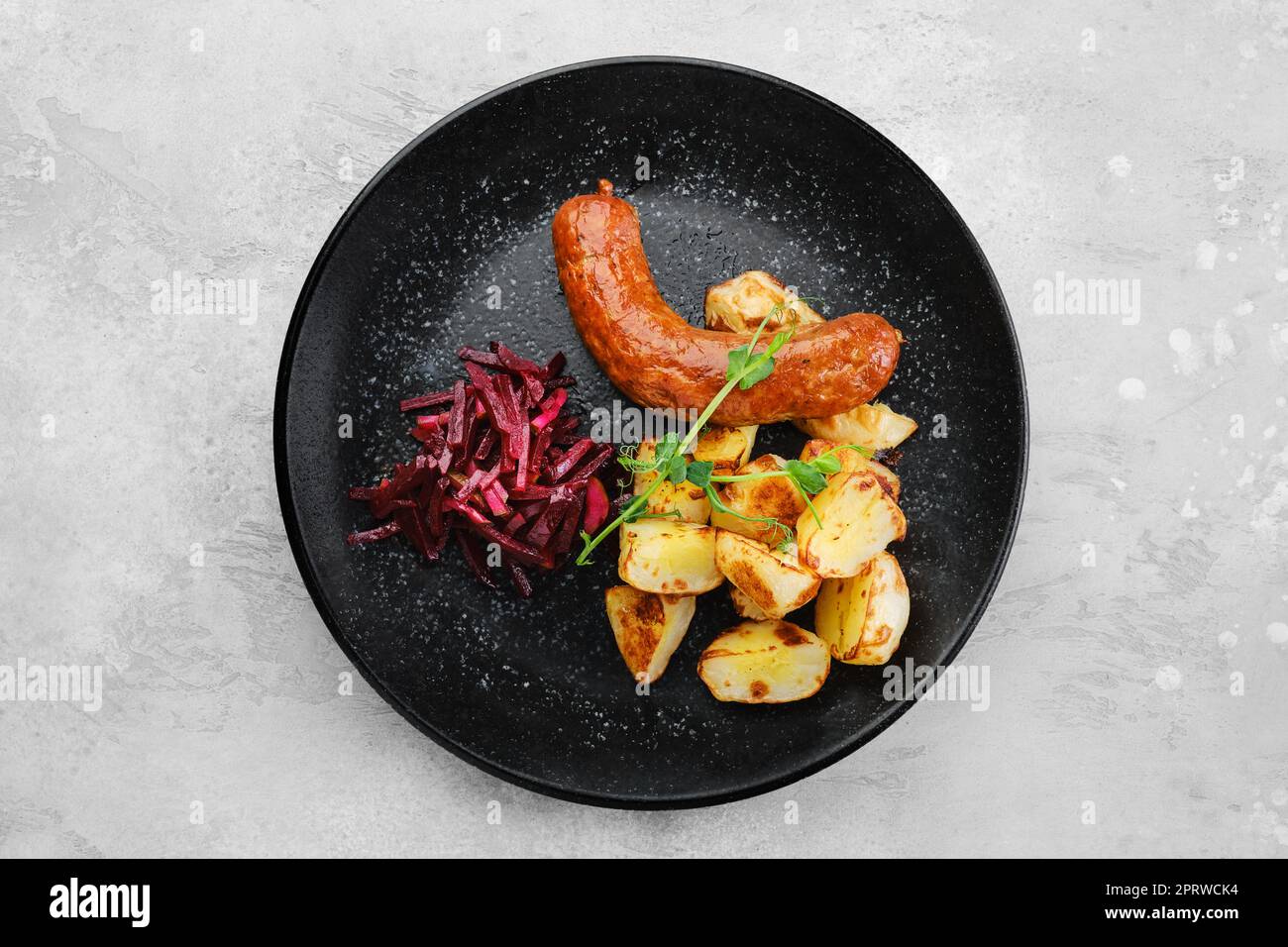 Gebratene Wurst mit Scheiben gekochter Kartoffeln, in Öl gebraten und marinierte Rüben, Draufsicht Stockfoto