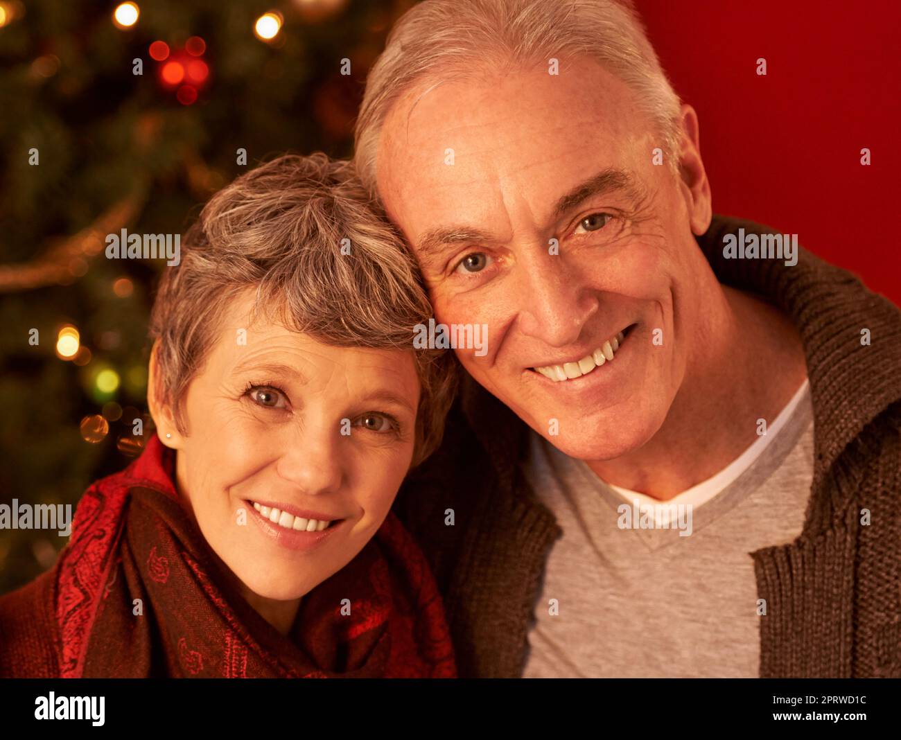 Es ist die schönste Zeit des Jahres. Ein zugeschnittenes Porträt eines glücklichen reifen Paares vor einem Weihnachtsbaum. Stockfoto