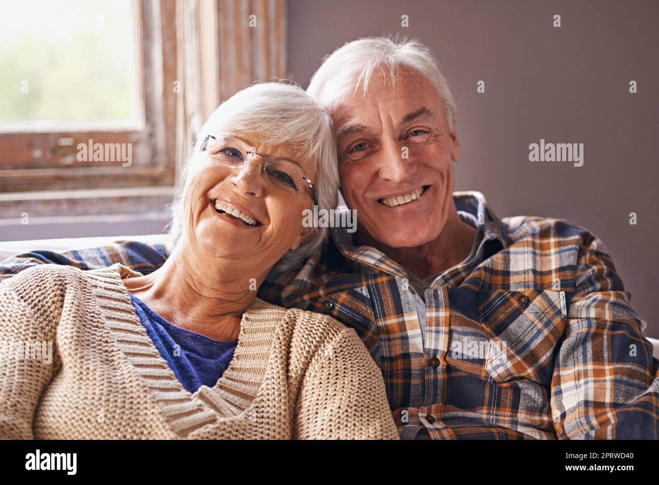 Was wollen wir mehr, wenn wir uns gegenseitig haben. Ein Porträt eines glücklichen älteren Paares, das zu Hause in ihrem Wohnzimmer sitzt. Stockfoto