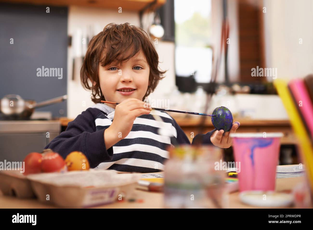 Eifrig mein osterei malen. Porträt eines kleinen Jungen, der ein blaues Ei malt. Stockfoto