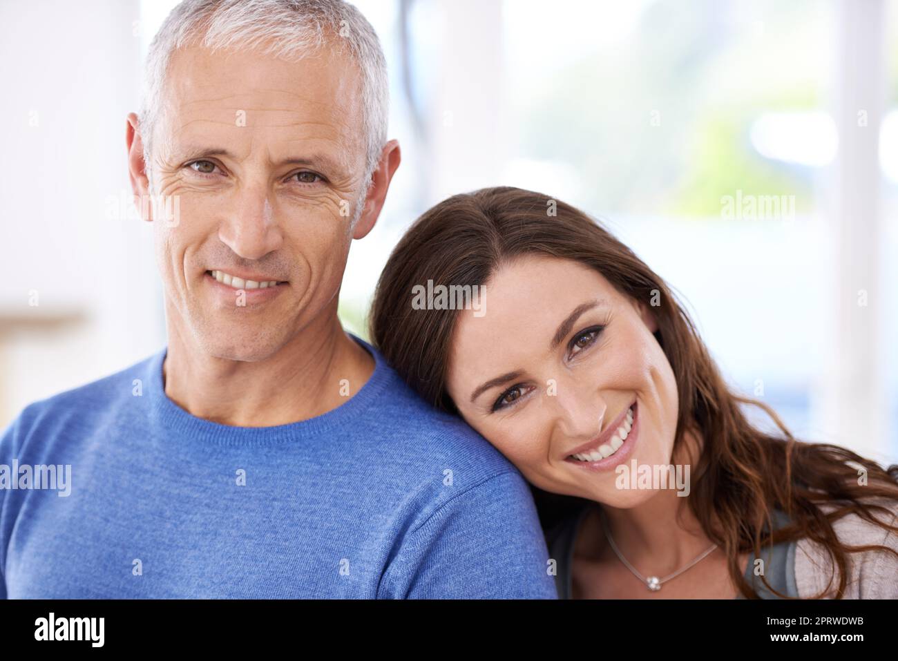 So verliebt. Eine junge Frau, die ihren Kopf auf der Schulter ihres reifen Mannes ruht. Stockfoto